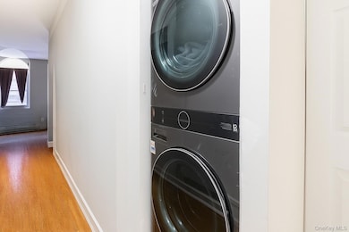 Laundry room with wood finished floors and stacked washer / drying machine