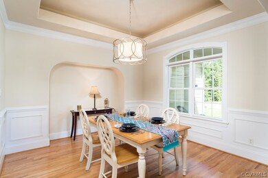 Dining room with moldings, tray ceiling, recessed arch, and oak wood floors.