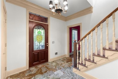 Entrance foyer with crown molding and a chandelier