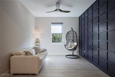 Den with decorative accent wall ceiling fan