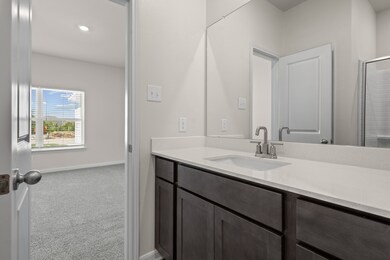 Bathroom featuring light colored carpet, vanity, a shower with door, and recessed lighting