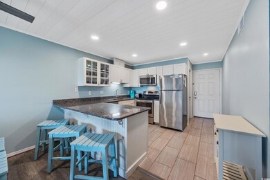 Kitchen featuring appliances with stainless steel finishes, a peninsula, glass insert cabinets, recessed lighting, and a kitchen breakfast bar