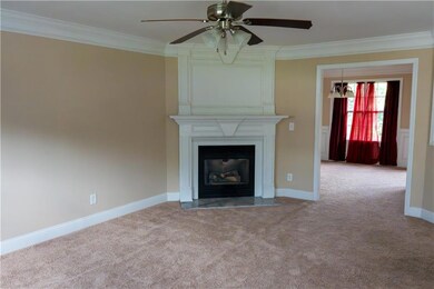 Unfurnished living room with carpet, ornamental molding, a ceiling fan, a large fireplace, and baseboards