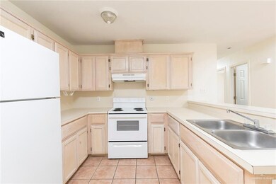 Kitchen featuring light brown cabinetry, white appliances, light countertops, light tile patterned floors, and under cabinet range hood
