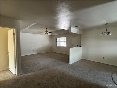 Unfurnished living room featuring carpet flooring, a textured ceiling, a chandelier, and ceiling fan