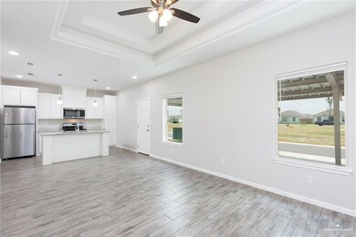Unfurnished living room with ceiling fan, light wood-style floors, a tray ceiling, and recessed lighting
