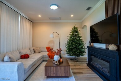 Living area featuring ornamental molding, wood finished floors, a glass covered fireplace, and recessed lighting
