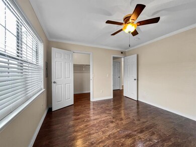 Unfurnished bedroom with a spacious closet, ceiling fan, crown molding, and dark wood-type flooring