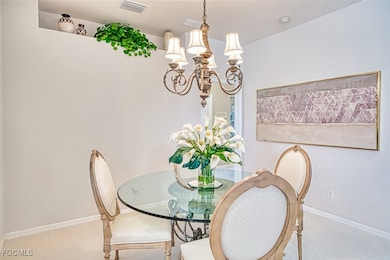 Carpeted dining room featuring a chandelier and baseboards