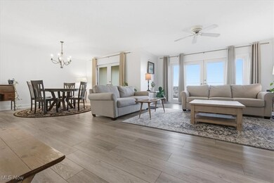 Living room with light wood-type flooring, a chandelier, ornamental molding, and ceiling fan