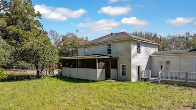 Back of property with a sunroom, a deck, and a law