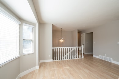 Empty room with light wood-style flooring and a chandelier