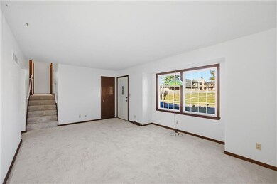 Unfurnished living room with light colored carpet and stairs