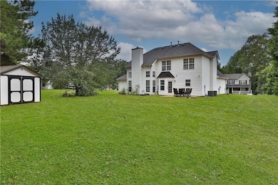 Rear view of house with a yard, a patio, a chimney, and a storage shed