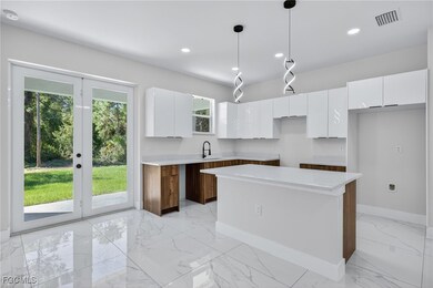 Kitchen with white cabinets, light marble finish floors, pendant lighting, modern cabinets, and a kitchen island