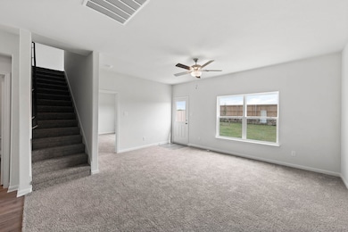 Unfurnished living room featuring stairs, ceiling fan, and carpet floors
