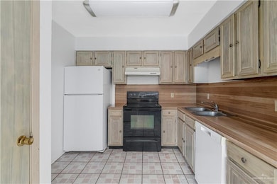 Kitchen with white appliances, tasteful backsplash, light countertops, and under cabinet range hood