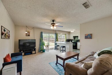 Living room featuring light carpet, a textured cei