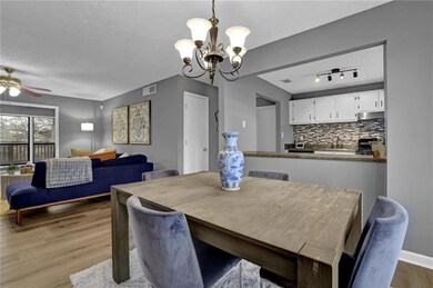 Dining area featuring wood finished floors, a chandelier, ceiling fan, and a textured ceiling