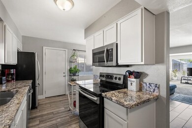 Kitchen featuring appliances with stainless steel finishes, white cabinetry, dark stone counters, and light wood-type flooring