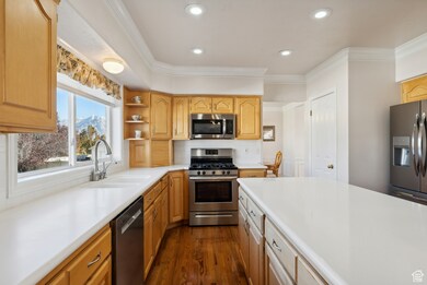 Kitchen with appliances with stainless steel finishes, light countertops, recessed lighting, dark wood-style flooring, and ornamental molding