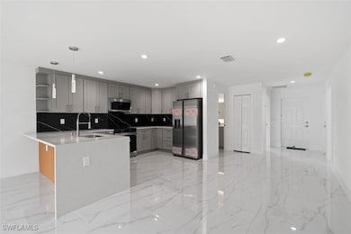 Kitchen with open shelves, gray cabinets, light marble finish floors, appliances with stainless steel finishes, and decorative light fixtures