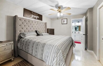 Bedroom with sink, light tile flooring, ensuite bath, and ceiling fan