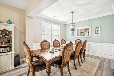 Dining area featuring light wood-style flooring, ornamental molding, and a wainscoted wall