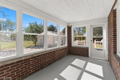 Unfurnished sunroom featuring brick wall and concrete flooring