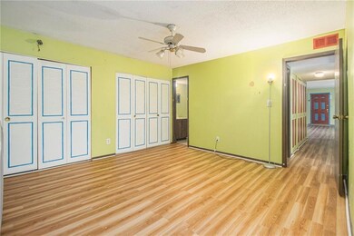Unfurnished bedroom featuring light wood-style floors, two closets, a textured ceiling, ensuite bathroom, and a ceiling fan