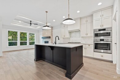 Kitchen featuring white cabinets, decorative backsplash, ceiling fan, decorative light fixtures, and a tray ceiling