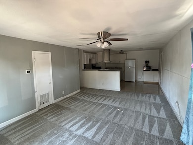 Unfurnished living room featuring light carpet and ceiling fan