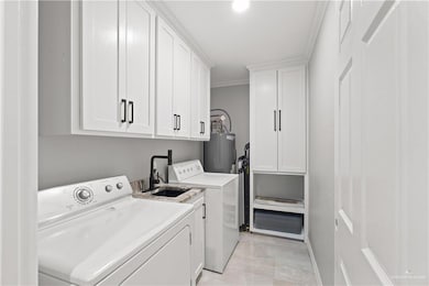 Laundry area with cabinet space, washing machine and dryer, water heater, and crown molding