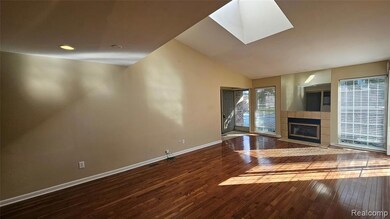 Unfurnished living room featuring dark wood-style floors, lofted ceiling, a tiled fireplace, and a skylight