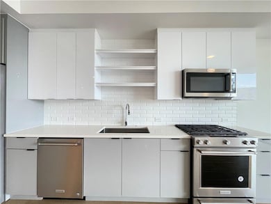 Kitchen with stainless steel appliances, open shelves, modern cabinets, and tasteful backsplash