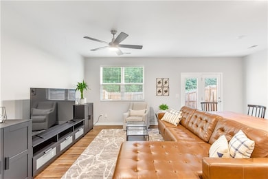 Living room with light wood-style floors, a ceiling fan, and baseboards