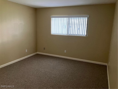 Spare room featuring dark colored carpet and baseb