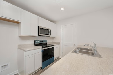 Kitchen with white cabinets, black range with elec