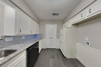 Kitchen with light stone countertops, black dishwa
