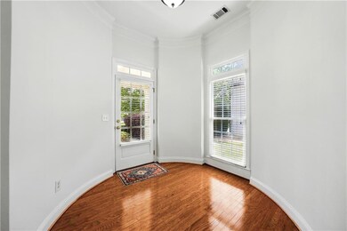 Doorway to outside featuring wood finished floors, ornamental molding, and a towering ceiling