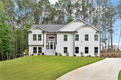 View of front of property featuring board and batten siding, a front lawn, roof with shingles, and driveway
