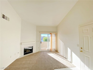 Unfurnished living room featuring carpet floors and a tiled fireplace