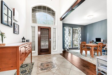 Step into the foyer adorned with wood beam accents, a custom stone mosaic medallion, custom paint, and beautiful tile floors. High ceilings and large windows fill the space with ample natural light. To the right, the formal dining room seamlessly flows into the kitchen.