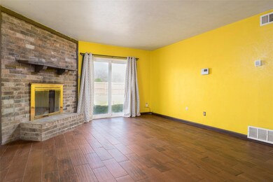 Unfurnished living room with a brick fireplace, wo