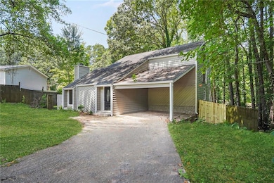 View of front of house with a carport, driveway, a chimney, and roof with shingles
