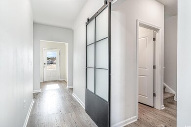 Corridor featuring light wood-style flooring, baseboards, and a barn door
