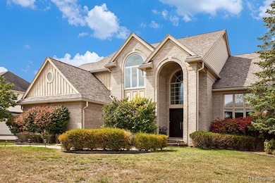 View of front of house with brick siding, a front lawn, roof with shingles, and a garage