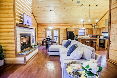 Living area featuring wooden ceiling, high vaulted ceiling, a fireplace, dark wood-style flooring, and wooden walls