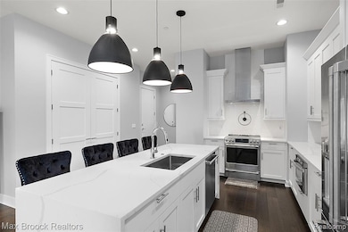 Kitchen with a center island with sink, white cabinets, light stone counters, hanging light fixtures, and recessed lighting