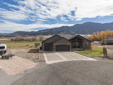 View of front of house featuring an attached garage, a mountain view, driveway, and stone siding